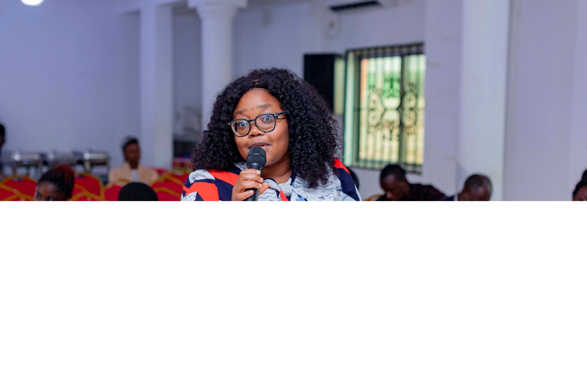 Colloquium participant in glasses speaking with a microphone during a Q&A session at the GRA Inaugural Colloquium