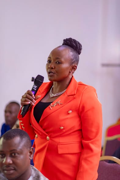 Colloquium participant in an orange blazer speaking into a microphone during a Q&A session at the GRA Inaugural Colloquium