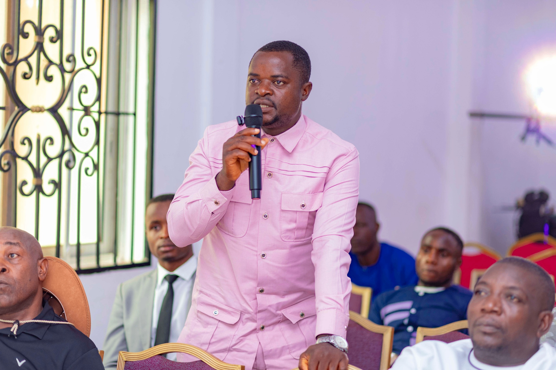 Colloquium participant in a pink shirt asking a question with a microphone during a Q&A session at the GRA Inaugural Colloquium