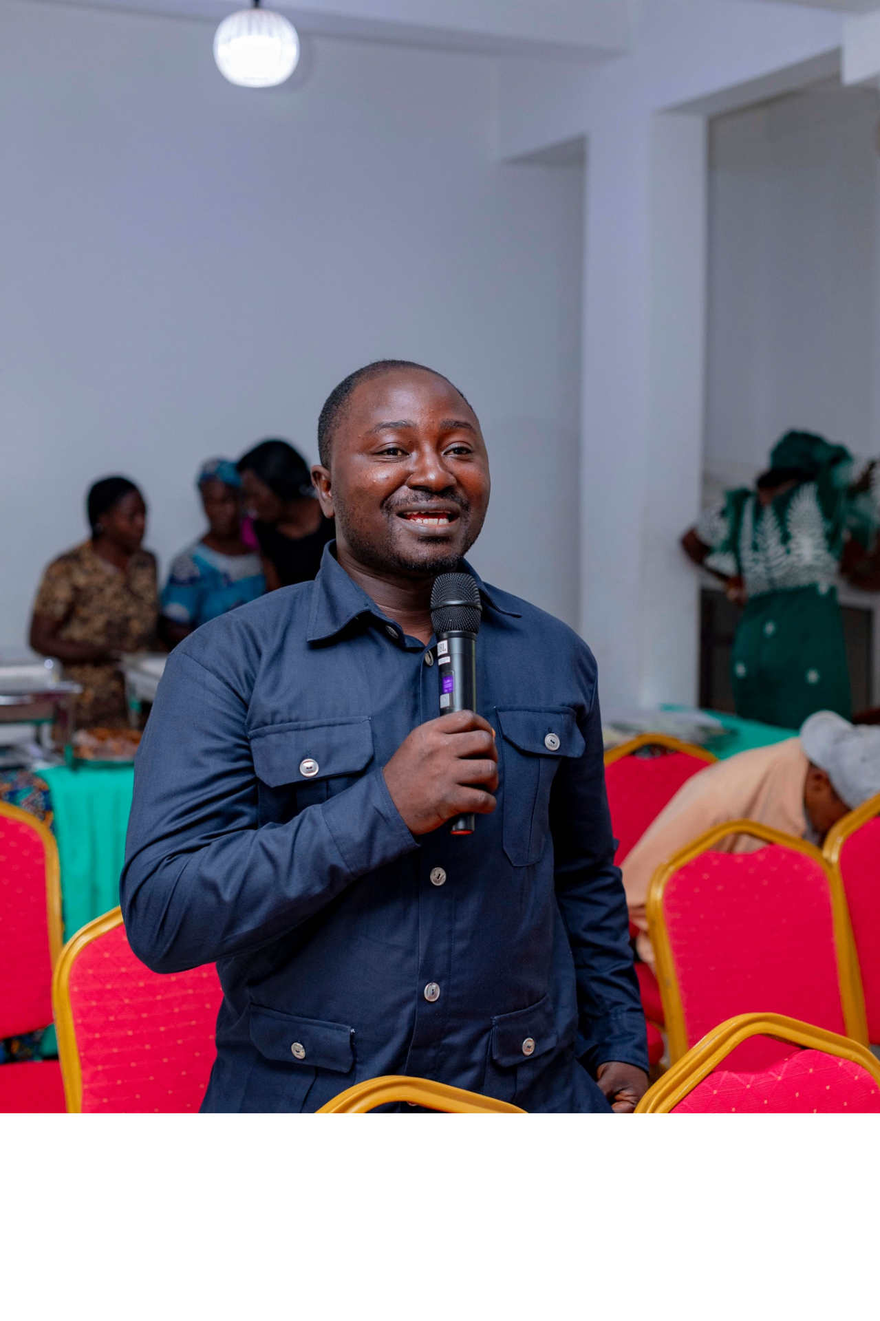 Colloquium participant in a navy shirt smiling with a microphone during a Q&A session at the GRA Inaugural Colloquium