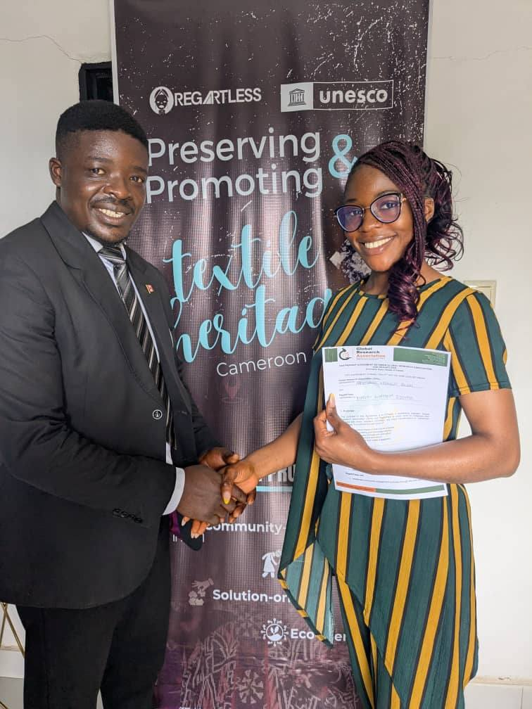 GRA representative and RegArtless representative shaking hands and holding the signed partnership agreement in front of a RegArtless × UNESCO banner